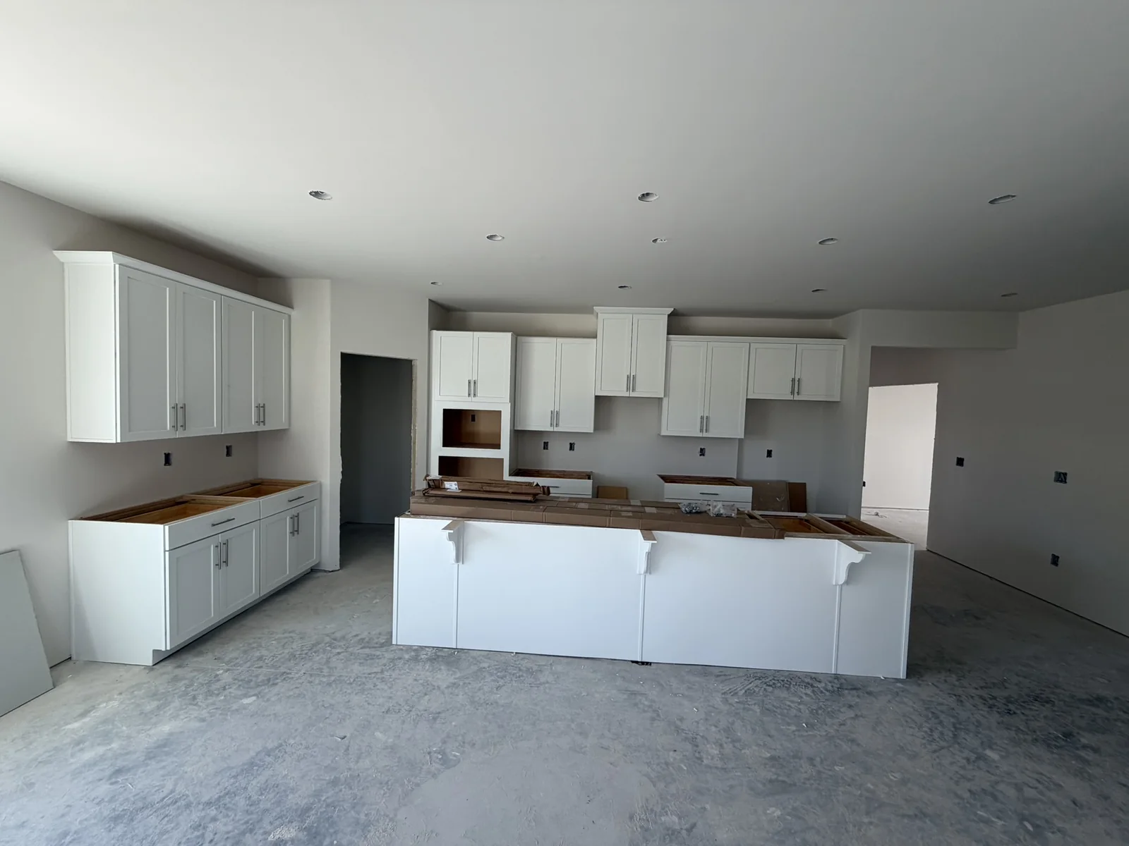 White kitchen wall cabinets and paneled island during installation