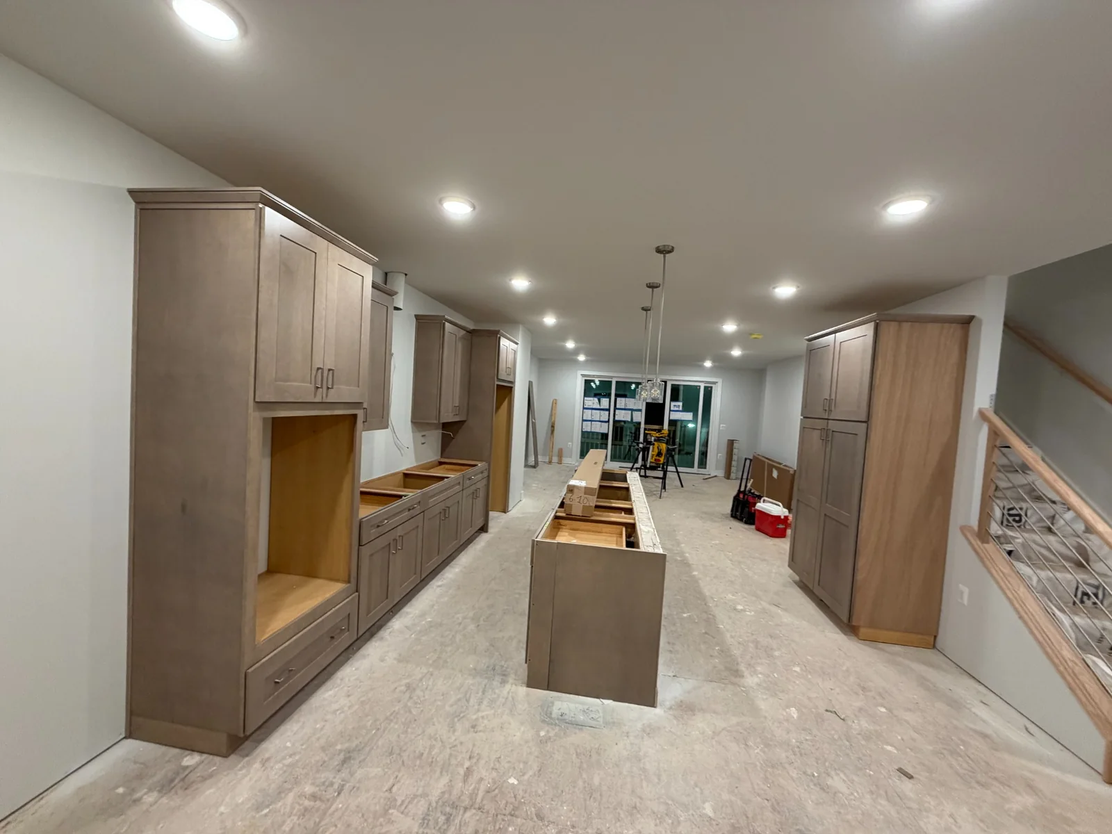 Wide view of wood-tone kitchen cabinets, an island and a tall pantry