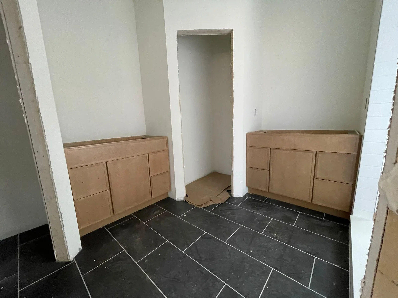 Two wood-tone bathroom vanity cabinets beside a central storage opening