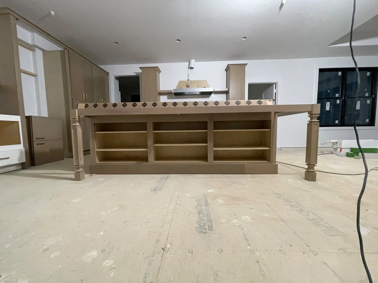 Front view of a wood-tone island with open shelving and decorative support legs